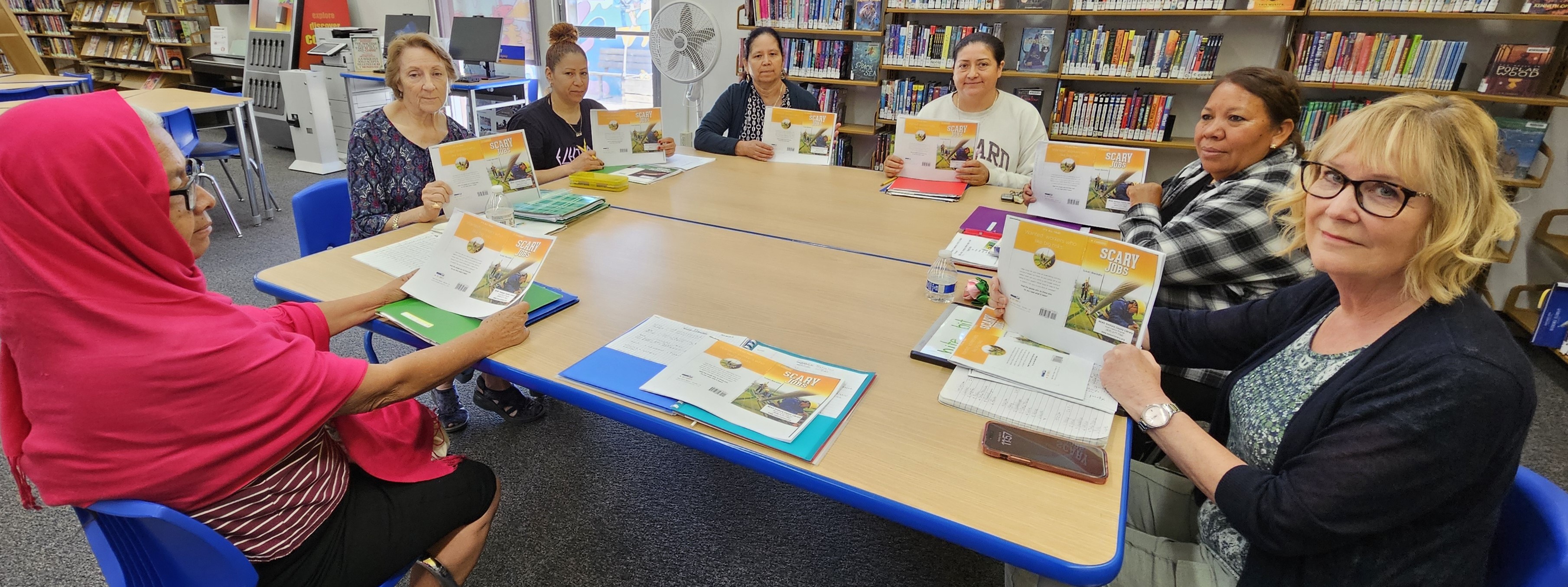 Photo of adult learners sitting around a table as they participate in English Conversation Group at the Albert H. Soliz Library.