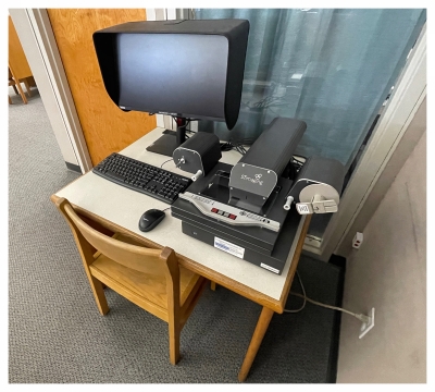 Microfilm machine on desk. Blue curtain in background.