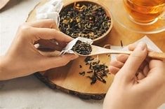 hand filling a tea bag with loose leaf tea