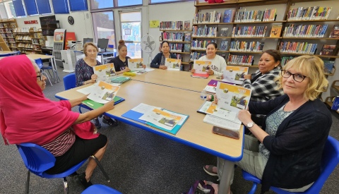 group of adult learners sitting at a table inside the library holding a story. Call 805-677-7160 for more information